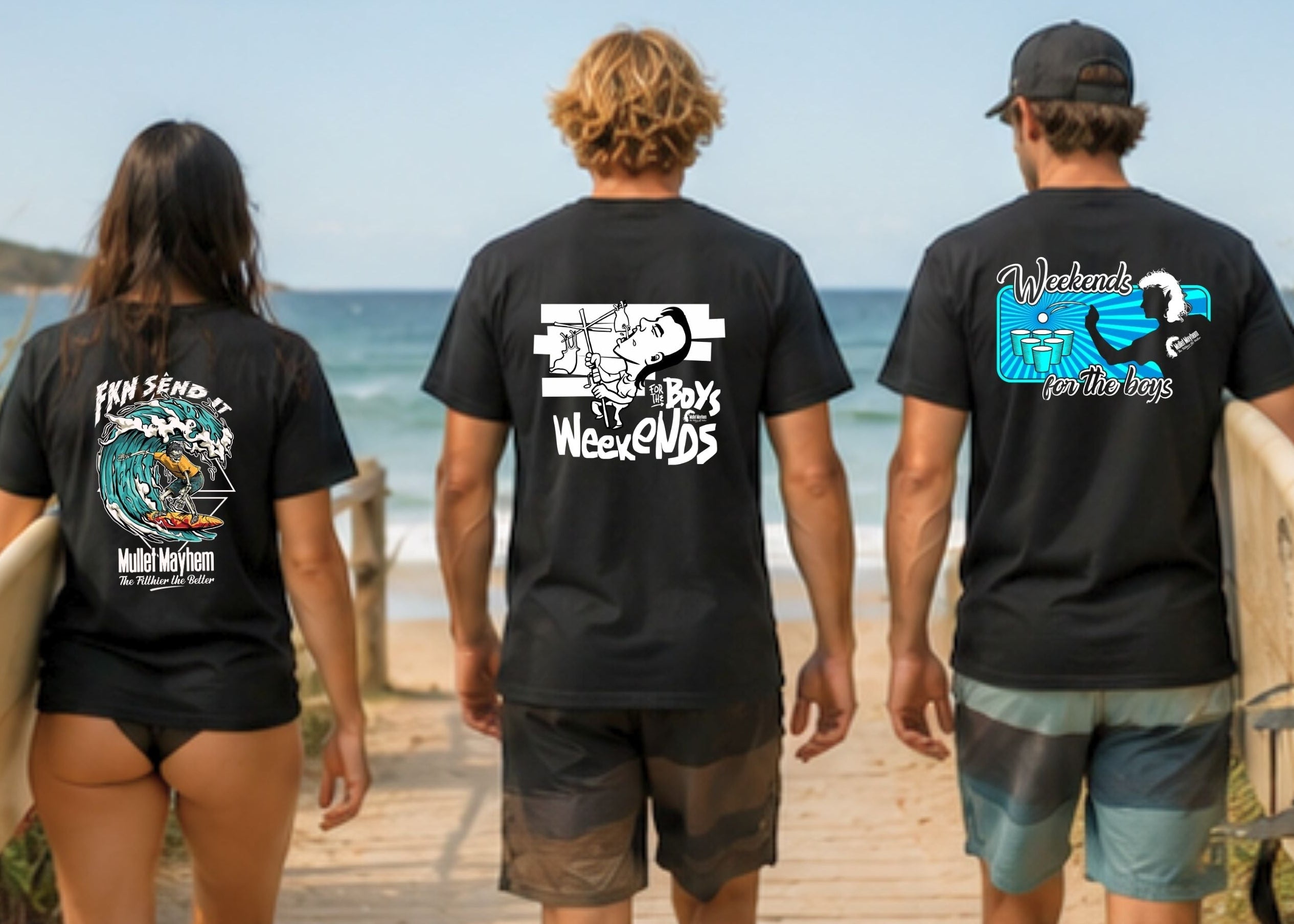 Three people standing on a boardwalk by the ocean, seen from behind, wearing matching black t-shirts with different surf-themed graphic designs. They are holding surfboards, with the beach and blue sky visible in the background.