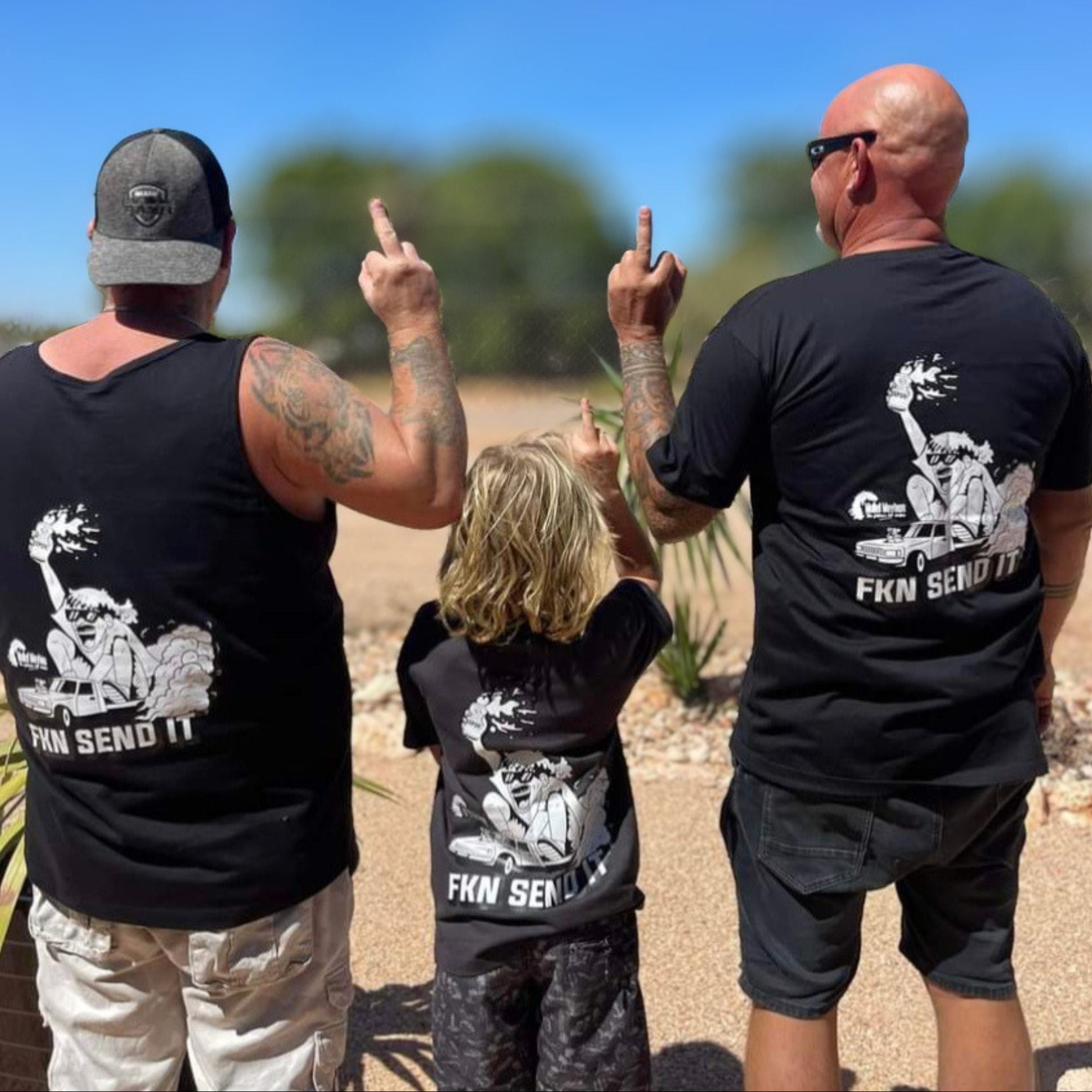 Three people wearing black t-shirts with graphic designs and text, standing outdoors.