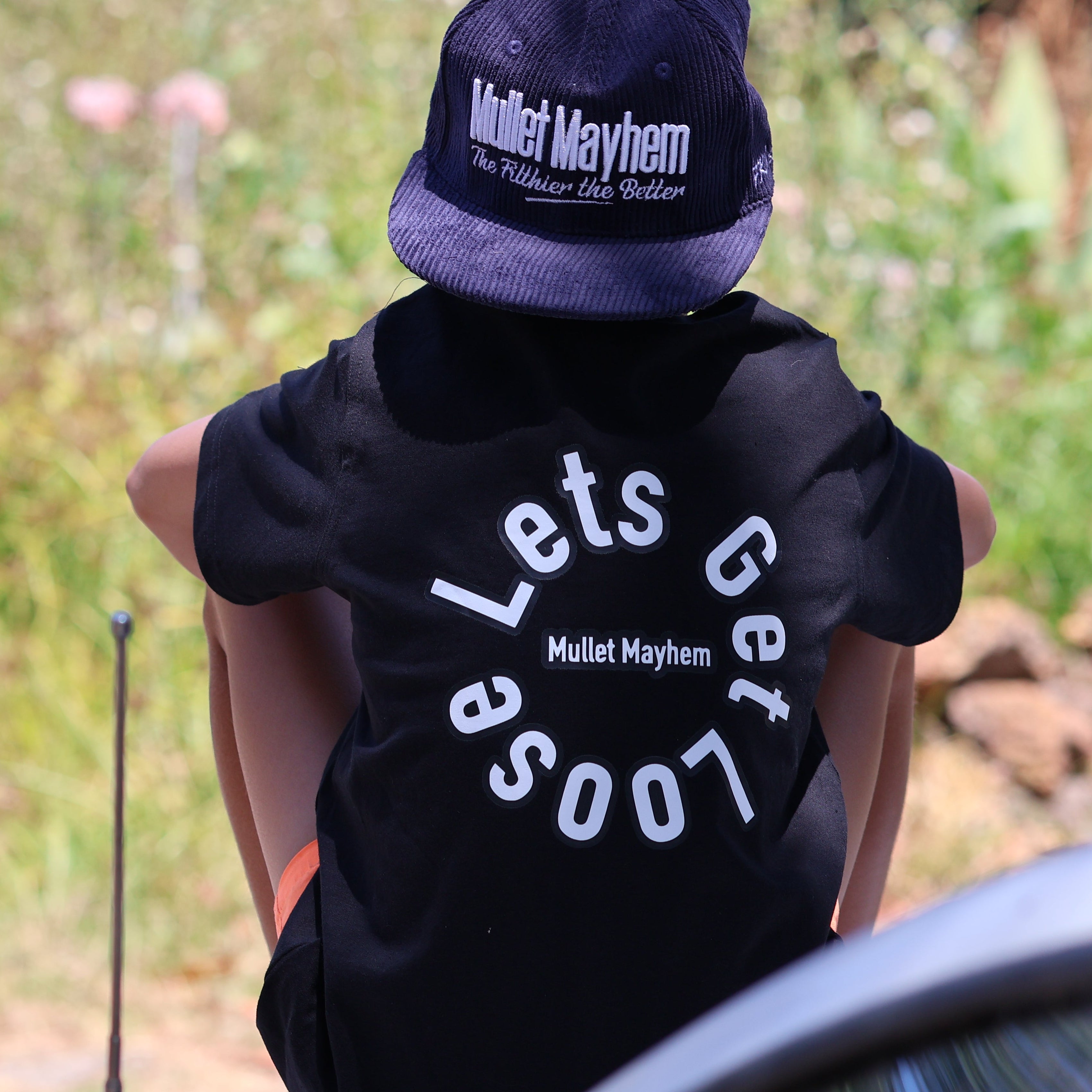 Person wearing a black hoodie with text and a matching cap in an outdoor setting